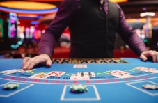 A close-up photo of a human dealer at a blackjack table in a real live casino