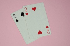 A pair of 2 value playing cards on a pink background 