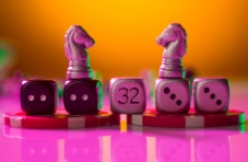 A photo of a row of wooden dice with the number 32 in the middle, and two chess pieces, on a bright pink background 