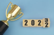 A photo of a golden champion cup and flipping numbers 2022 and 2023 on wooden blocks on a blue background