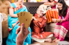 A photo of a happy family playing a card game with one member holding up a trio or Aces