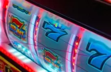 A close-up photograph of a slot machine at an online casino that features neon lighting and ‘7’ symbols. 