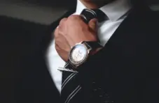 A close-up photo of a man wearing a smart dress suit and watch