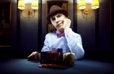 A photo of a man wearing a hat with a quizzical look on his face and chip stacks in front of him