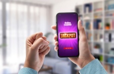 A hand holding a mobile phone displaying a jackpot win at a casino against a blurry background